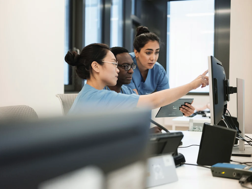 SIMStaion Medical staff in scrubs working together at computer workstation, reviewing patient data and simulation results.