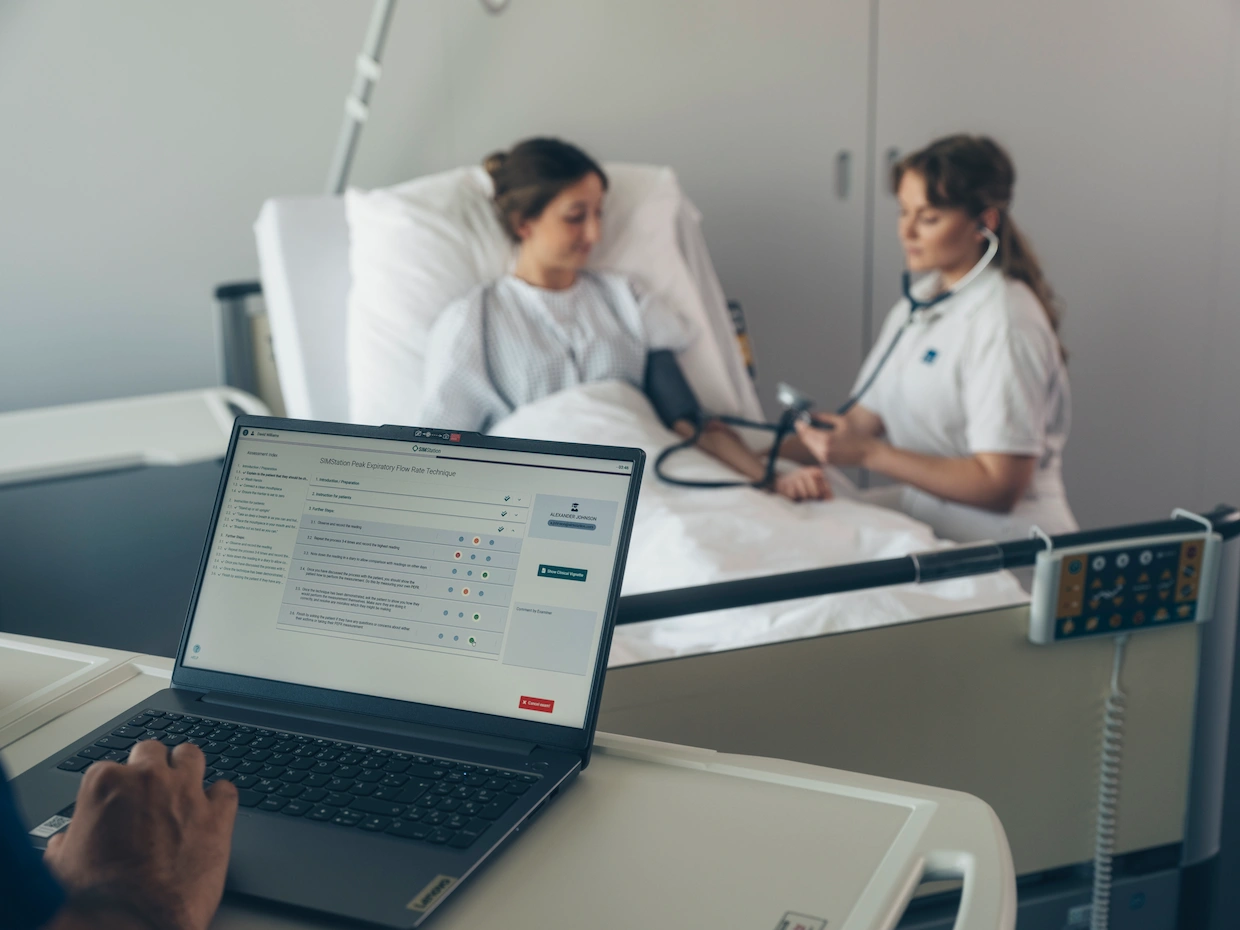 Hospital simulation training showing healthcare professional measuring patient blood pressure while digital sepsis screening form is used for early detection.