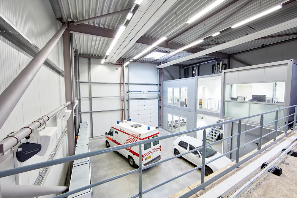 Modern emergency services facility with ambulance and SUV parked indoors, featuring modular office and training space.