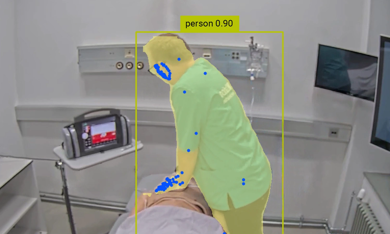 A person in medical scrubs leans over a mannequin on a hospital bed, possibly performing a procedure, in a clinical setting enhanced by SIMStation AI-Powered Insights for Simulation Training, with medical equipment visible in the background.