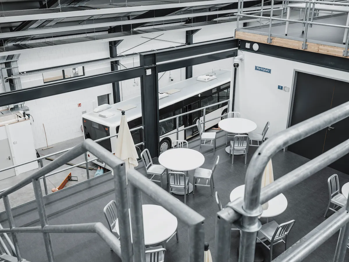 An overhead view of a large-scale simulation facility featuring a cafe-style training area and a full-sized bus for integrated in-situ emergency response drills.