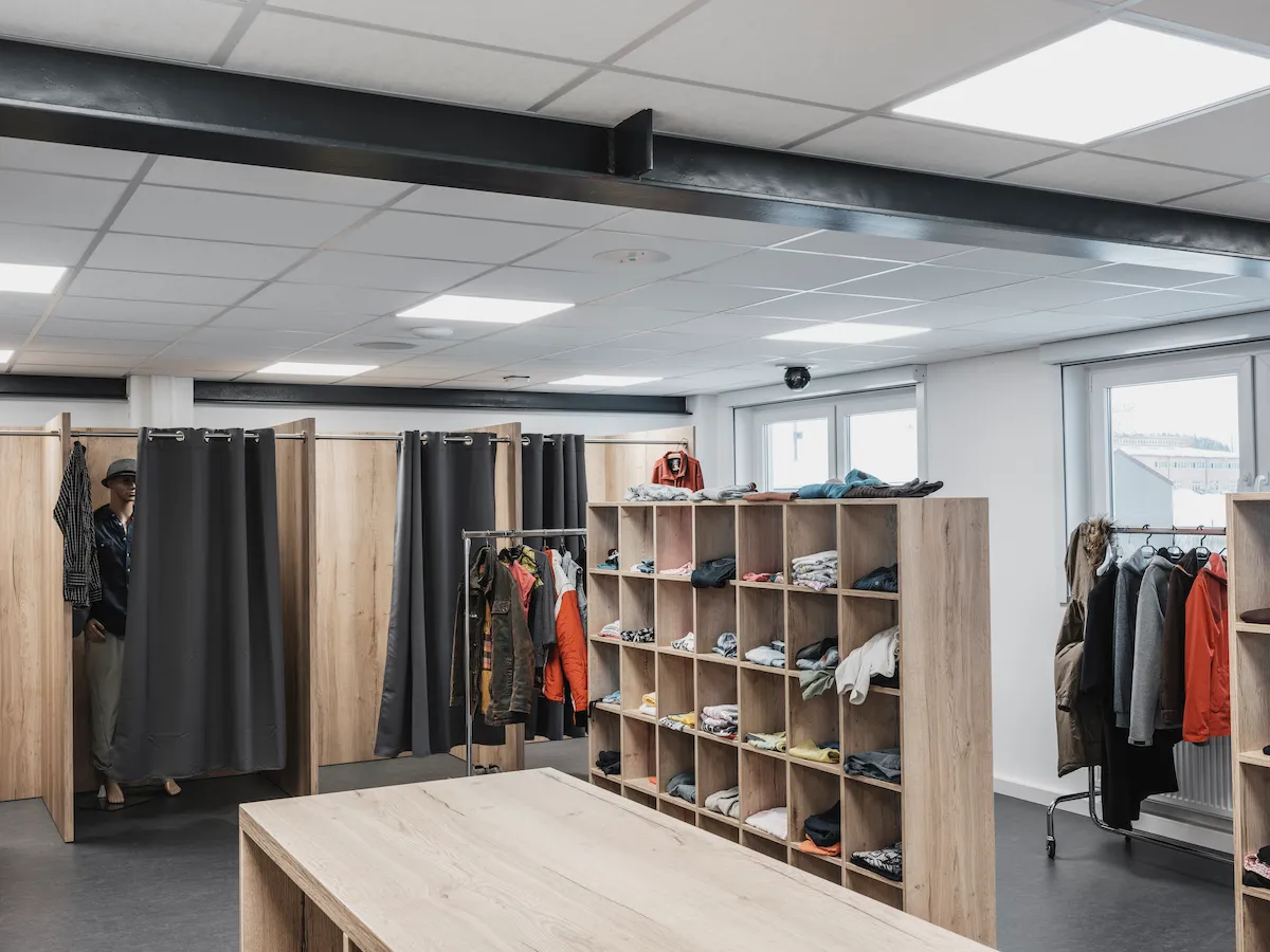 A realistic retail simulation room featuring clothing racks, dressing rooms, and manikins used for behavioral analysis and public safety training.
