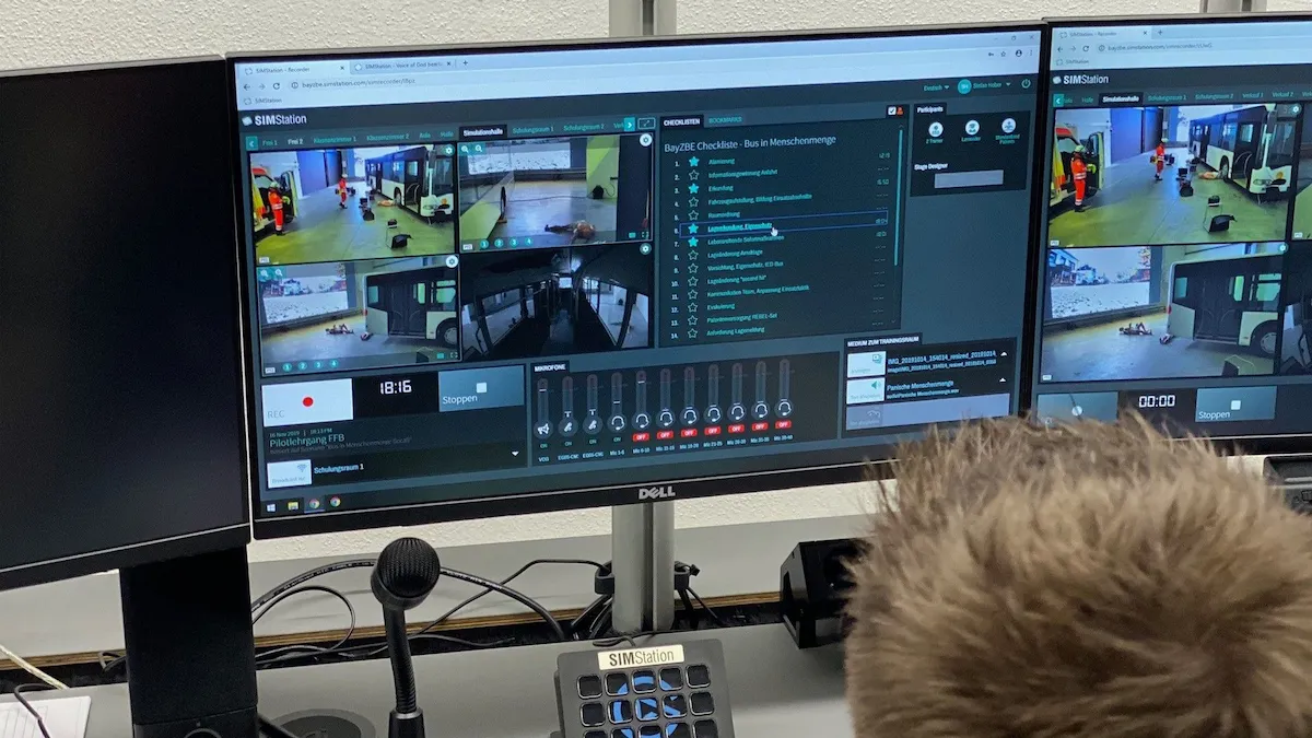 Close-up of a monitor running SIMStation recording software, showcasing a multi-view camera layout of a bus simulation alongside a digital performance assessment checklist for real-time evaluation.