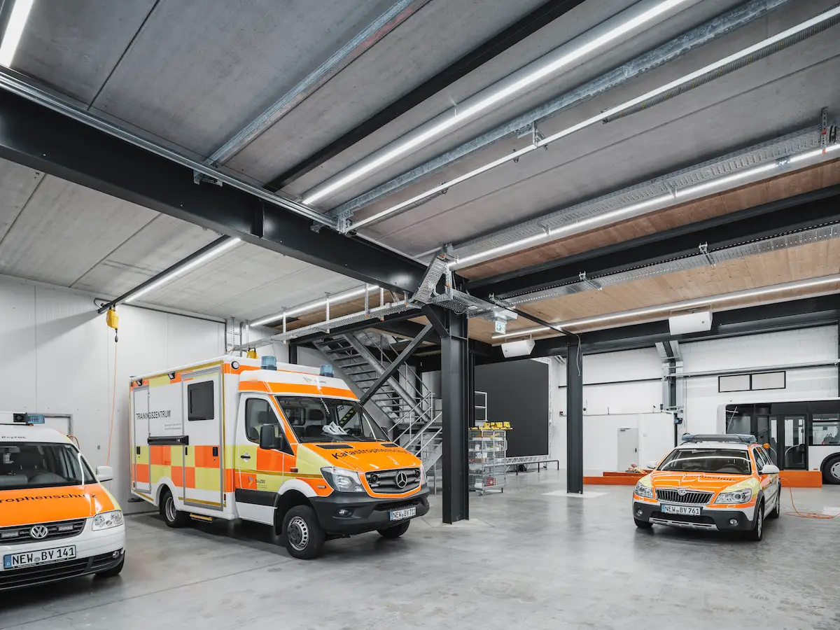 BayZBE SIMStation Axis collaboration in a modern training center featuring orange ambulances and emergency vehicles.