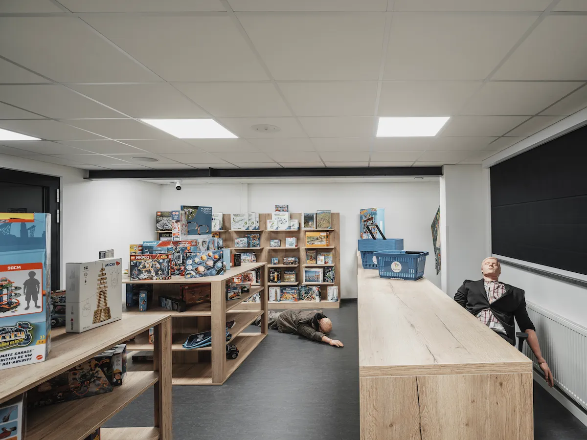 A simulated retail store environment stocked with toys and games, featuring manikins staged for a medical emergency or public safety training scenario.