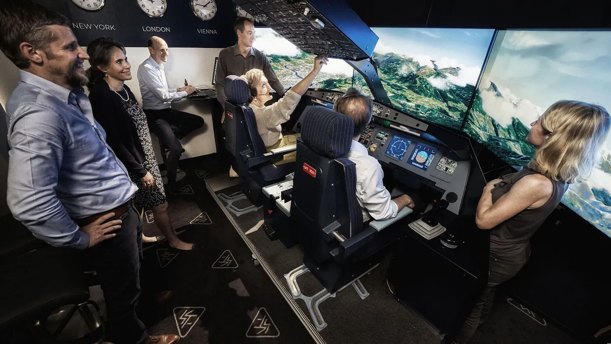 A multidisciplinary team conducting high-pressure performance training in a realistic Airbus flight simulator, featuring an immersive three-screen cockpit display and specialized flight deck controls for behavioral team analysis.