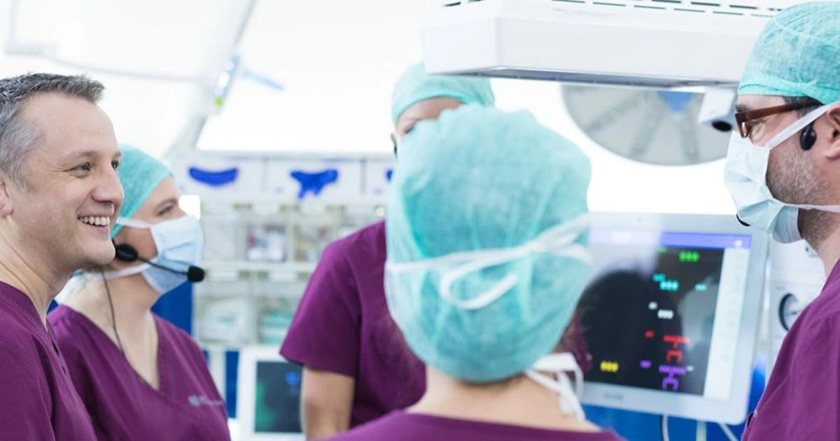 A surgical team in a hospital operating room wearing scrubs and communication headsets, engaging in professional collaboration and effective team performance during a medical simulation.