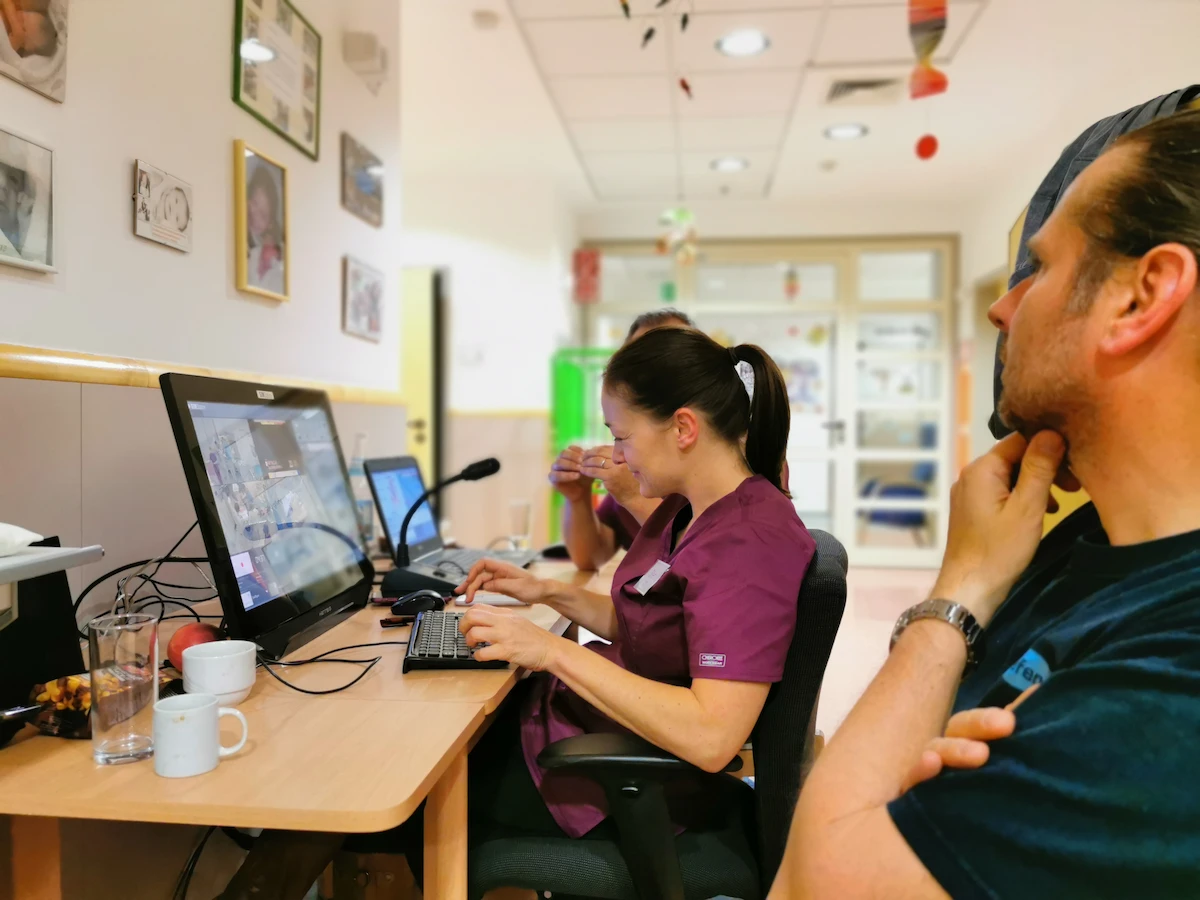 A clinical simulation team in a hospital setting using SIMStation software on multiple monitors to observe, record, and evaluate a live medical training exercise.